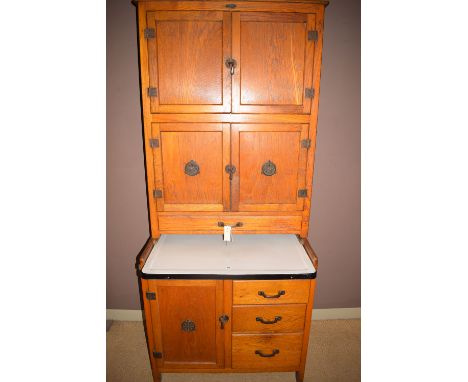 A ''Maidsaver'' kitchen cabinet in oak, maker's label, two cupboards over a sliding enamel top, the base containing three dra