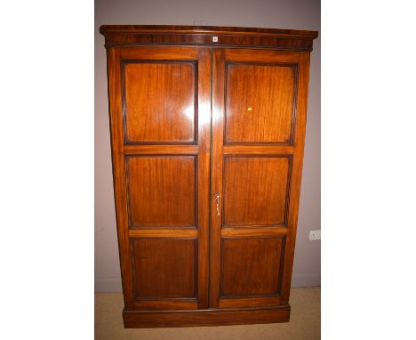 A Victorian mahogany two door panel cupboard, raised on a plinth base opening to reveal shelves and brass hooks.