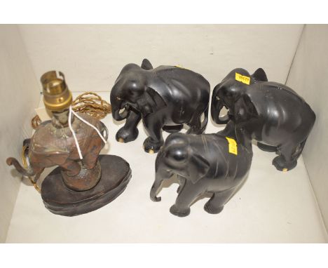 Three carved ebony models of elephants; and a small table lamp in the form of an elephant standing on a globe.