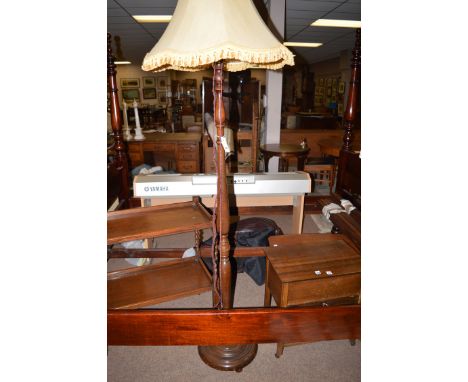 A stained wooden standard lamp on turned round base, with gold coloured shade.