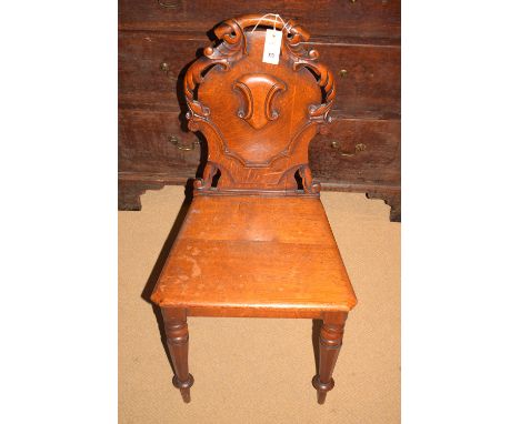 A 19th Century carved and stained oak hall chair, with carved back panel and solid seat, raised on turned and tapering octago