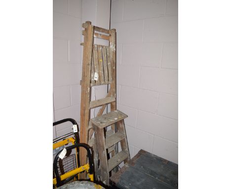 A six tread wooden step ladder; a four tread wooden step ladder; and a yellow and black painted metal barrow.
