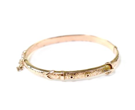 A 9ct gold hinged bangle in the form of a belt with engine turned decoration, in original box, stamped 375, approx 6.5g.