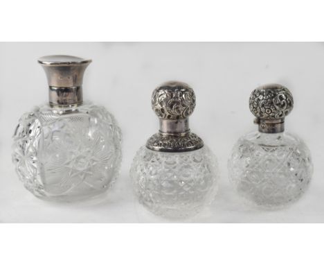 Three antique silver topped perfume decanters, height of largest 14cm, with a star and cross hatch cut design with silver lid