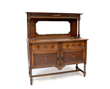 An early 20th century oak mirror back sideboard with carved upper frieze above bevelled mirror plate flanked by barleytwist s