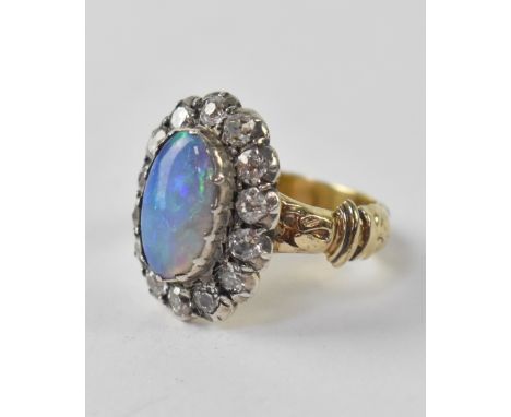 A vintage opal and diamond ring, a central oval opal with green with blue colour within a halo of fourteen small diamonds, ap