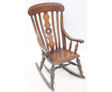 A 19th century provincial Windsor rocking chair with slatted back, sweeping arms, turned spindle supports, one-piece saddle s