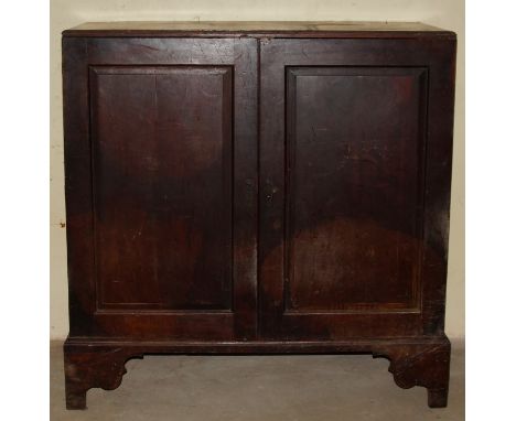 A George III mahogany low press cupboard, with two panelled doors, a single shelf with recesses for various shelves, flanked 