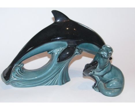 A 20thC Poole Pottery figure of a leaping dolphin, in black and turquoise, printed marks beneath, 20cm high, and a figure of 