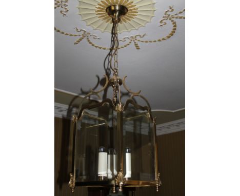 A brass lantern shaped light fitting, with four bevelled glass sides, chain suspension, the lantern 53cm high, 28cm wide.