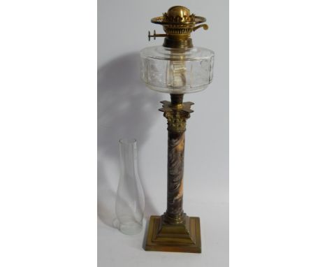 An Edwardian table oil lamp, with faceted clear glass reservoir, Corinthian column stem with marbled effect inset on a square