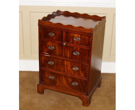 A George III mahogany night commode, with a shaped gallery above two false drawer doors above a double pull out drawer, on br