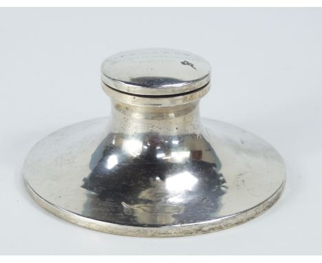 A George V silver capstan inkwell, Birmingham 1918, the hinged cover bearing inscription, with oak base, 16cm diameter.
