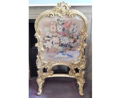 A 19thC rococo giltwood fire screen, with 'C' scroll frame and Berlin woolwork floral panel.