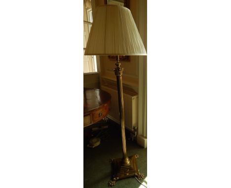 An early 19thC brass floor lamp, with a reeded Corinthian column, the square base applied with four paw feet, with a shade, 1