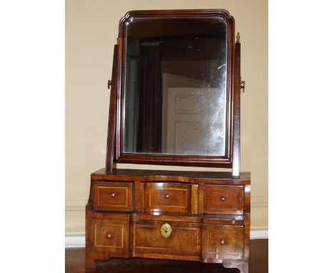 A walnut dressing table mirror, the rectangular plate on tapering supports, the stepped base with an arrangement of three sho