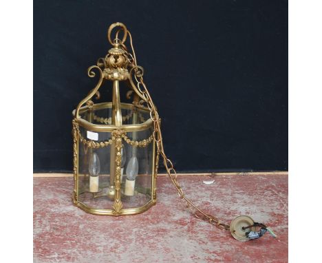 French-style gilt metal and glass lantern hall light, the cylindrical-shaped light decorated with applied scrolls and floral 