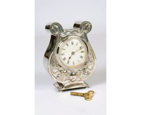 An Edward VII Art Nouveau silver cased mantel clock, embossed floral tendrils, the circular enamel dial with Roman numerals, 