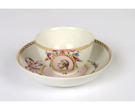 A Den Haag porcelain teacup and saucer, portrait medallions within gilt helixical frames surmounted by floral garlands and bo