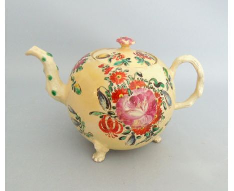 A Staffordshire creamware globular teapot and cover, decorated with floral sprays with a crabstock handle and standing on thr