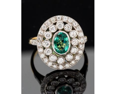 An emerald and diamond three tier oval cluster 18ct gold ring, the central oval emerald approximately 0.56 carat, the two row