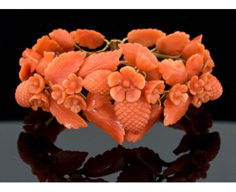 A Victorian coral and yellow gold hinged bangle, the carved floral leaf and hops design to yellow gold wirework bangle, front