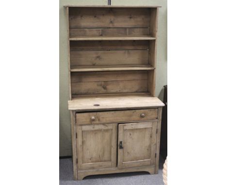 A small pine kitchen dresser. The upper section having two shelves, the lower cabinet with a single long drawer over a pair o