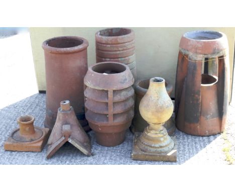 Five various terracotta chimney pots, three ridge tiles and other items. One of the chimey pots with a cowl, 62cm high overal