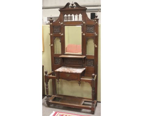 A mahogany hall stand. The heavily carved frame having a swan neck pediment and large bevelled edge mirror to the centre flan