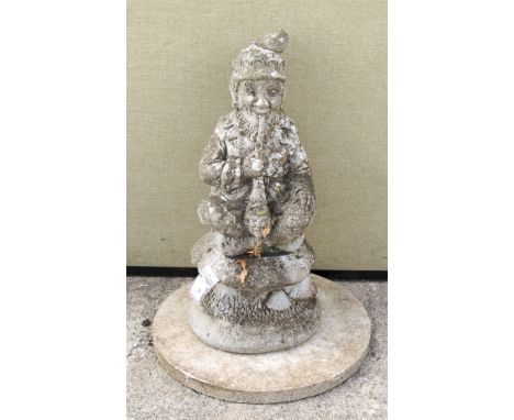 A weathered reconstituted stone figure of a jolly gnome. Modelled seated on a mushroom smoking a pipe, H65cm