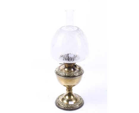 A English brass oil lamp. Having embossed scrolling decoration to the base, an etched floral shade and funnel, H44cm (excludi