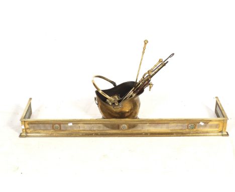 A brass fender and a selection of fire tools. The fender having pierced decoration and decorated with flowers, H13cm x W142cm
