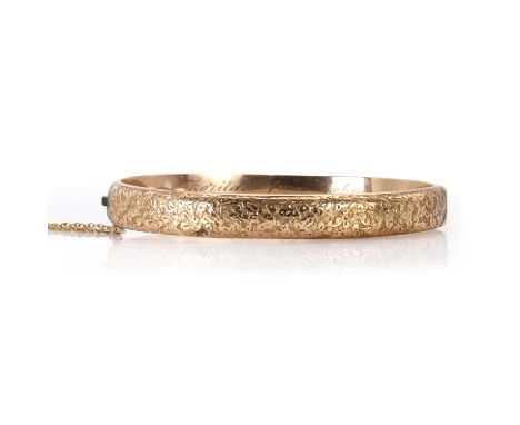 A late Victorian 9ct gold hinged bangle,  with a chased top half, Birmingham 1892. A presentation inscription to the inside d