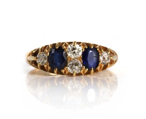 A late Victorian 18ct gold sapphire and diamond boat shaped ring,  with two oval cut sapphires, interspersed with old cut dia