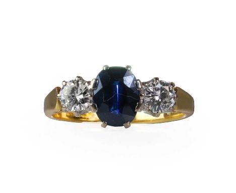 An 18ct gold diamond and sapphire three stone ring,  an oval mixed cut sapphire, 5.50mm x 7.50mm, flanked by two round brilli