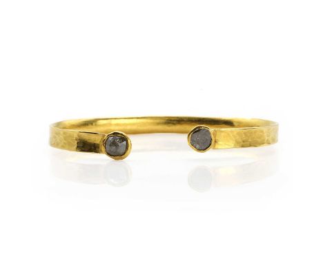A rough diamond and gold bangle, the bangle with hammered finish, each end set with a rough faceted diamond, in a rub over se