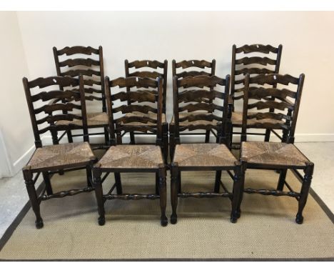 A set of eight North Country style beech and ash ladder back rush seat dining chairs on turned legs to pad and ball feet (6 p