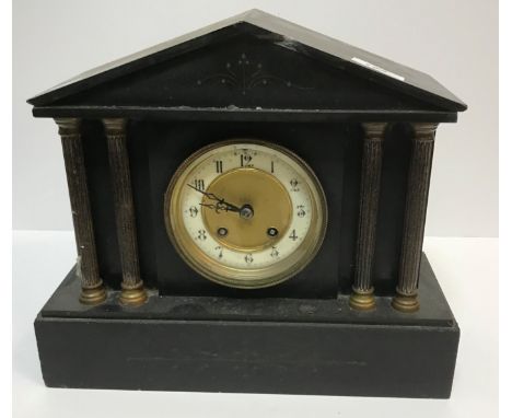 A late 19th Century French black slate cased mantel clock of architectural form with brass capped column decoration, the circ