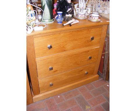 A contemporary light oak three drawer chest with square metal handles - width 84cm 