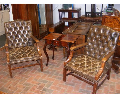 A pair of Regency style button back brown leather fire side armchairs