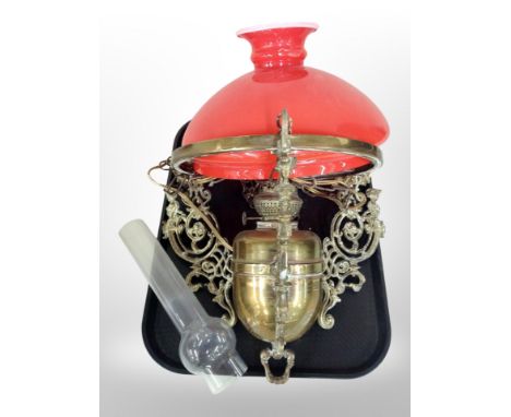 An early 20th century Continental brass hanging oil lamp with red shade 