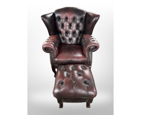 A Chesterfield oxblood button leather wingback armchair with matching footstool 