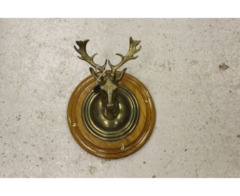 A brass whip rack in the form of a deer's head, mounted on an oak circular plaque CONDITION REPORTS Overall with wear and scu