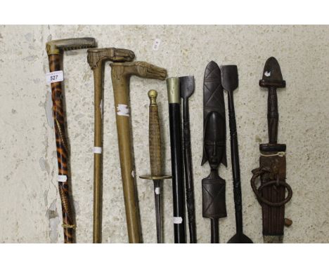 A collection of walking sticks to include a carved wooden walking stick with a horse head and moustached face inscribed "Kepk