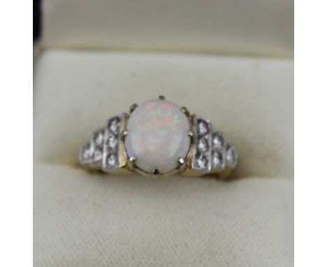 A LADY'S OPAL SET RING, the shoulders diamond set in rows of three, two and one (six on either shoulder) in an 18ct yellow go