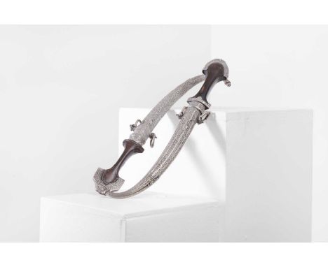 Two silver-mounted daggers or jambiyas, c.1900, Moroccan, each with curved blades and wood handles, mounted with profusely en