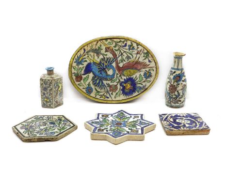 A collection of Qajar pottery late 19th century and later, comprising four tiles, including an oval example decorated with tw
