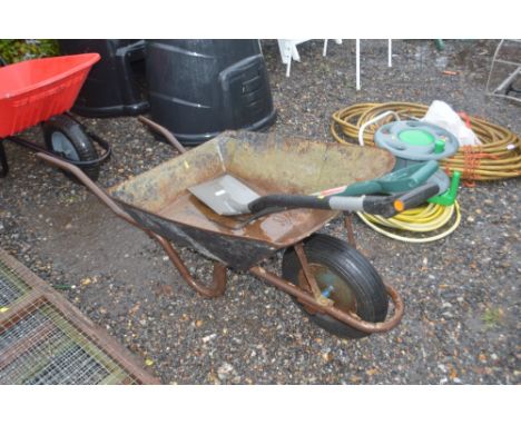 A metal wheelbarrow and contents of fork and spade