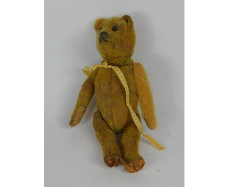 An early 20thC straw filled Teddy bear, with a moveable head and tail, black button eyes, 28.5cm high.