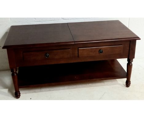 A reproduction mahogany coffee table with two lift up lids to reveal sectional interior for CD's, on turned legs with magazin